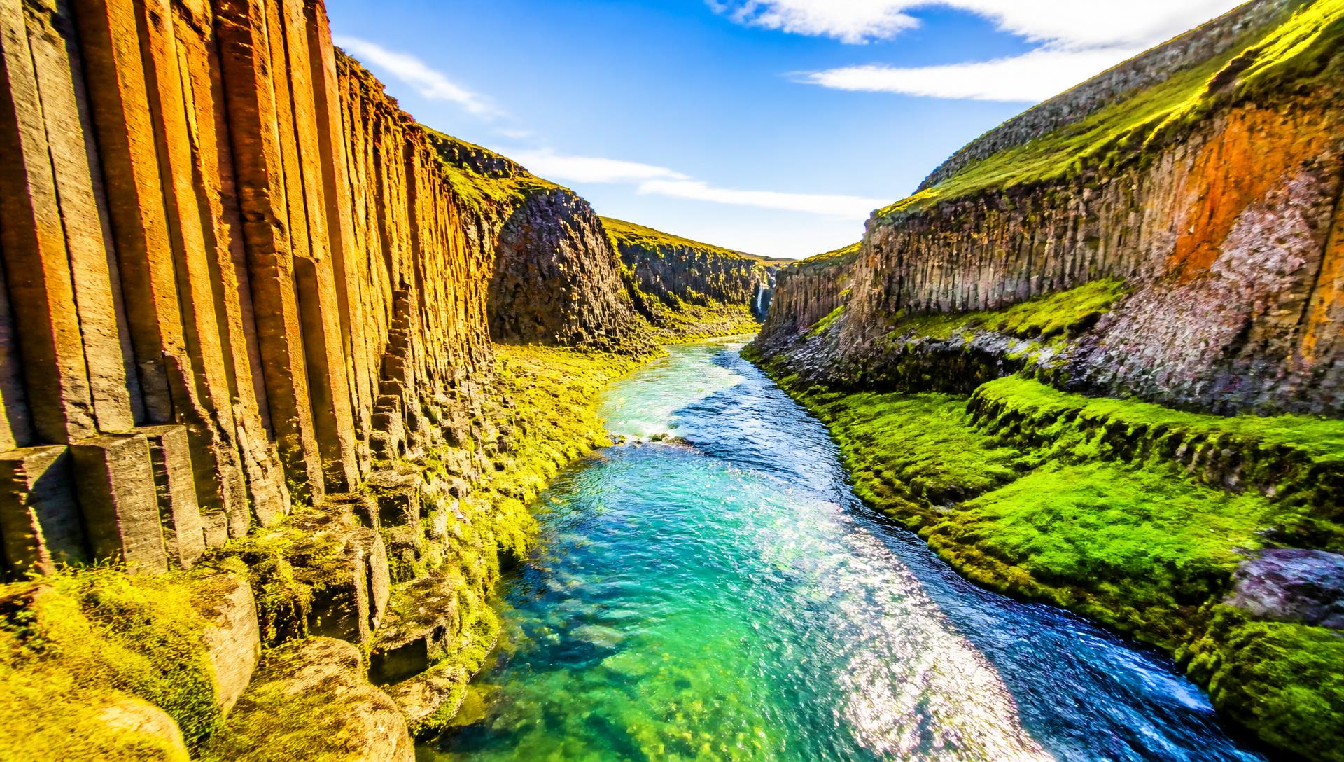 Steam rising from a turquoise natural hot spring pool among mossy Icelandic lava rock